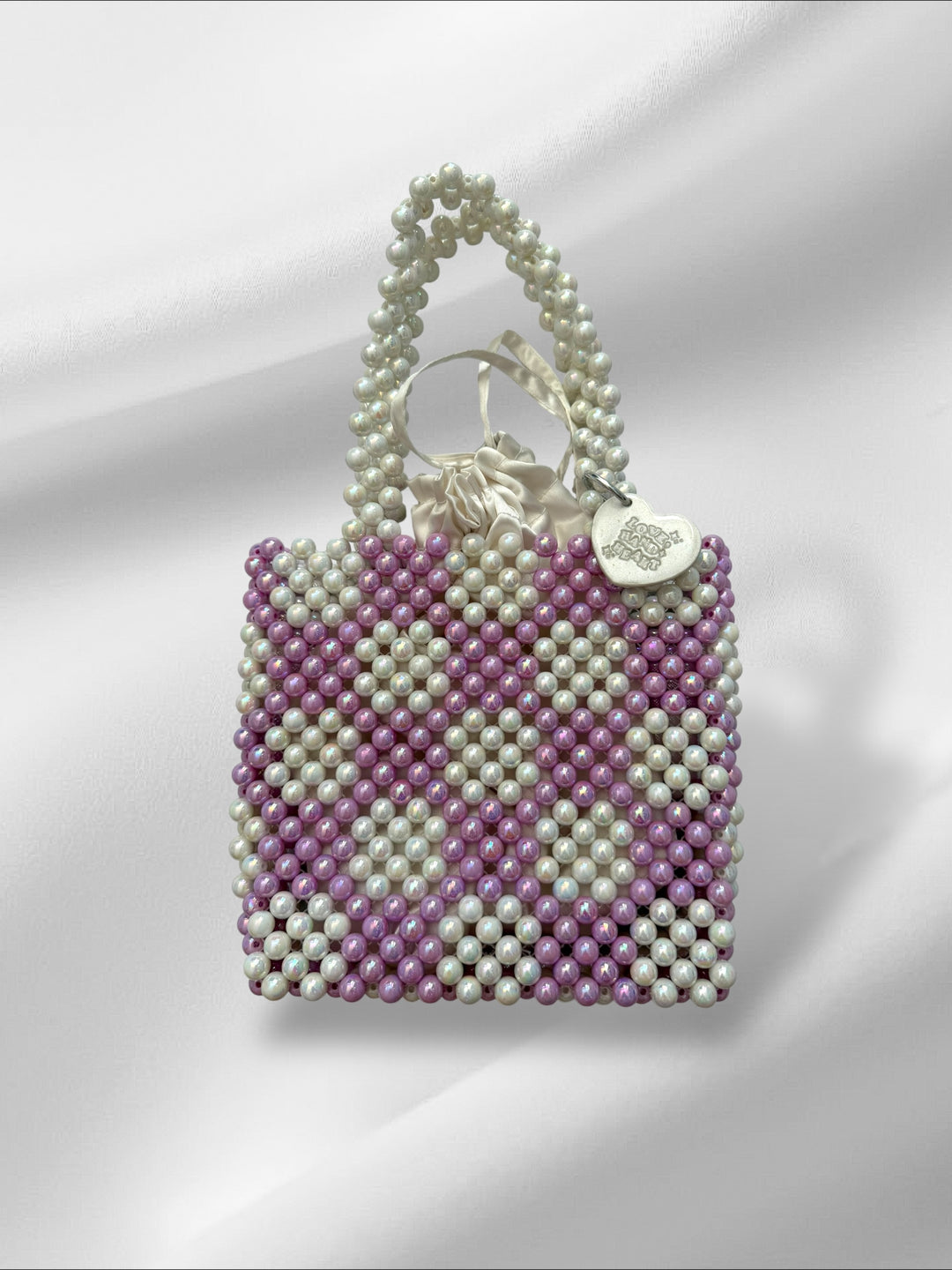 Beaded handbag with a keychain and drawstring pouch on a white background