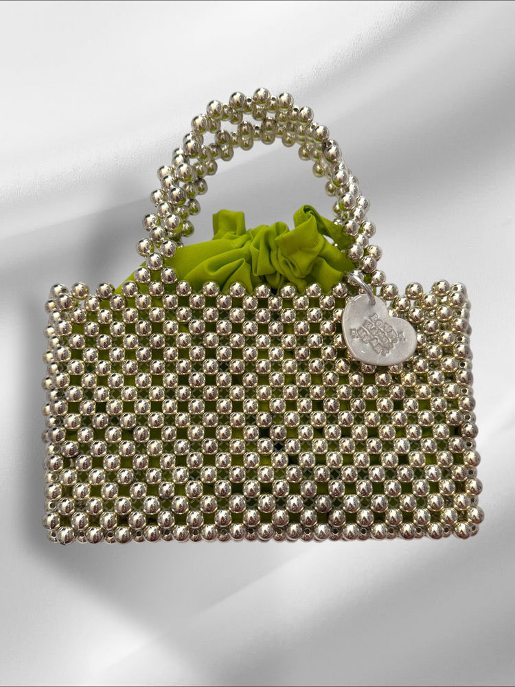 Handbag with discoball beads and a green drawstring pouch on a white background