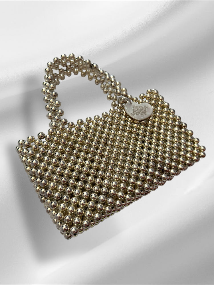 Silver beaded handbag with a heart tag on a white background