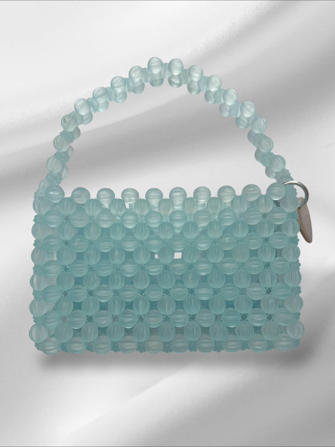 Light blue beaded handbag on a white background