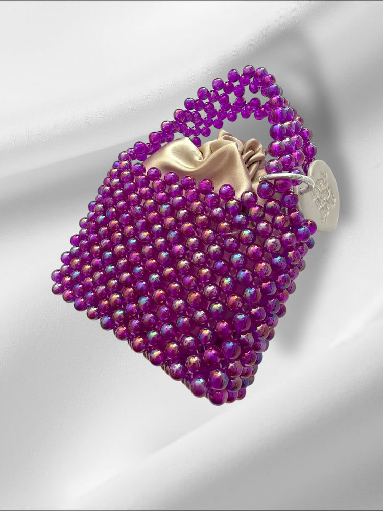 Purple beaded handbag with a gold interior on a white background