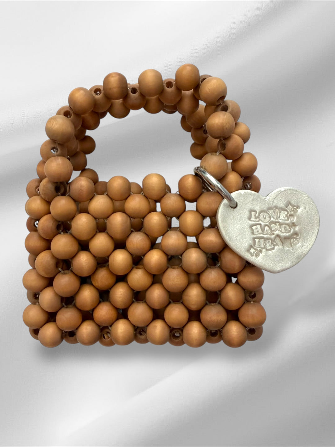Wooden beaded mini handbag with a silver charm on a white background
