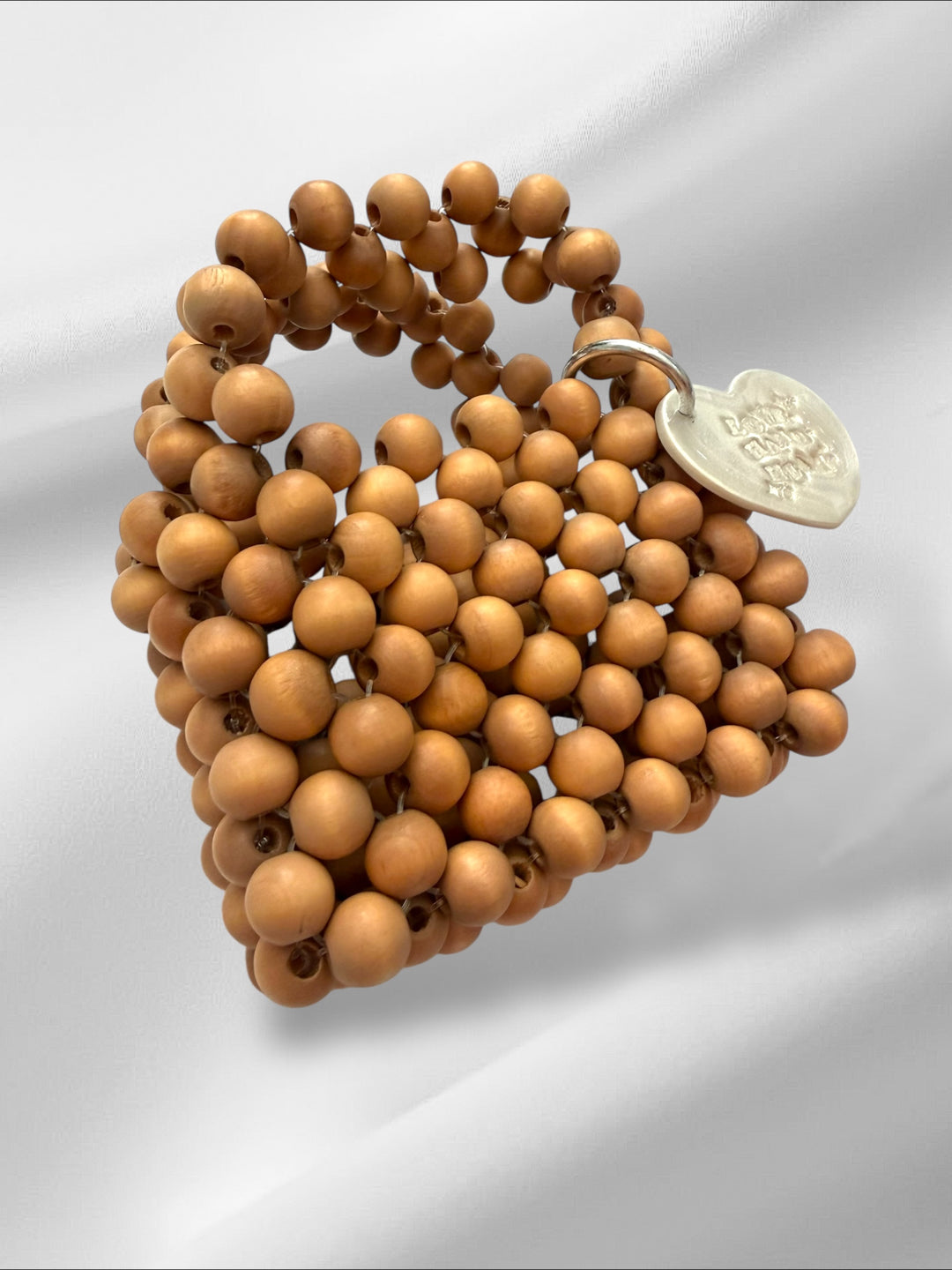 Wooden beaded mini purse with a silver tag on a light gray background