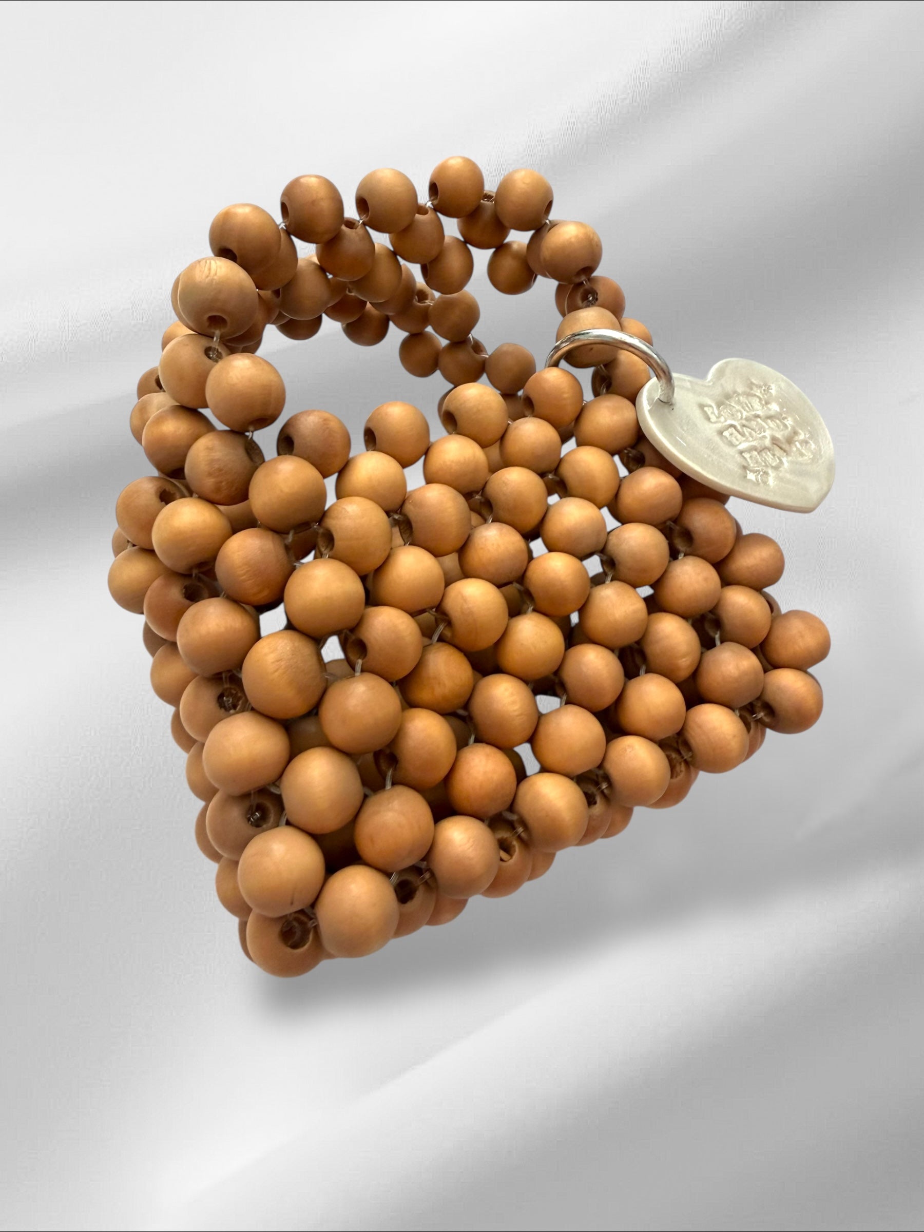 Wooden beaded mini purse with a silver tag on a light gray background