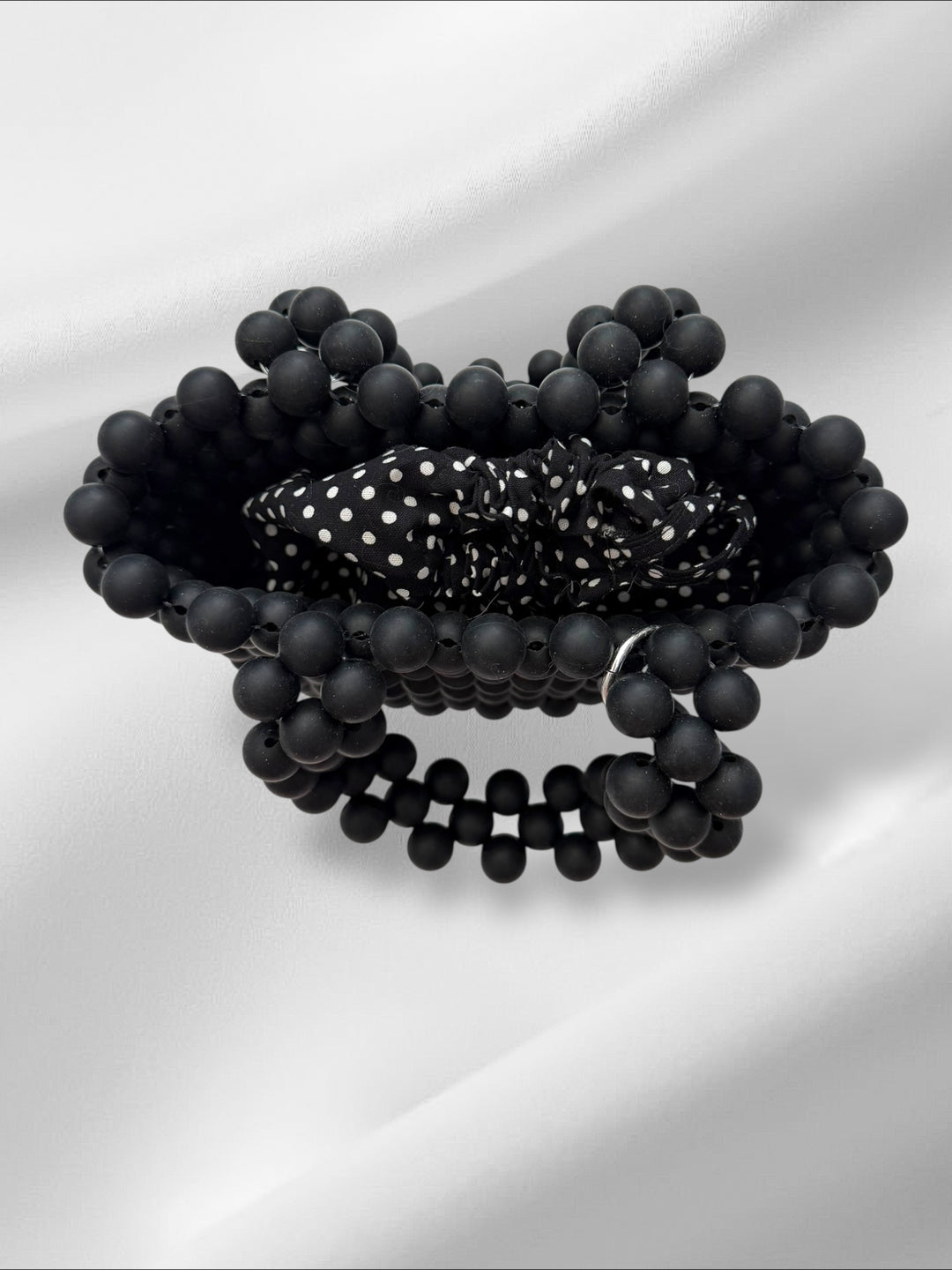 Black beaded handmade bag with a polka dot pattern drawstring pouch on a white background