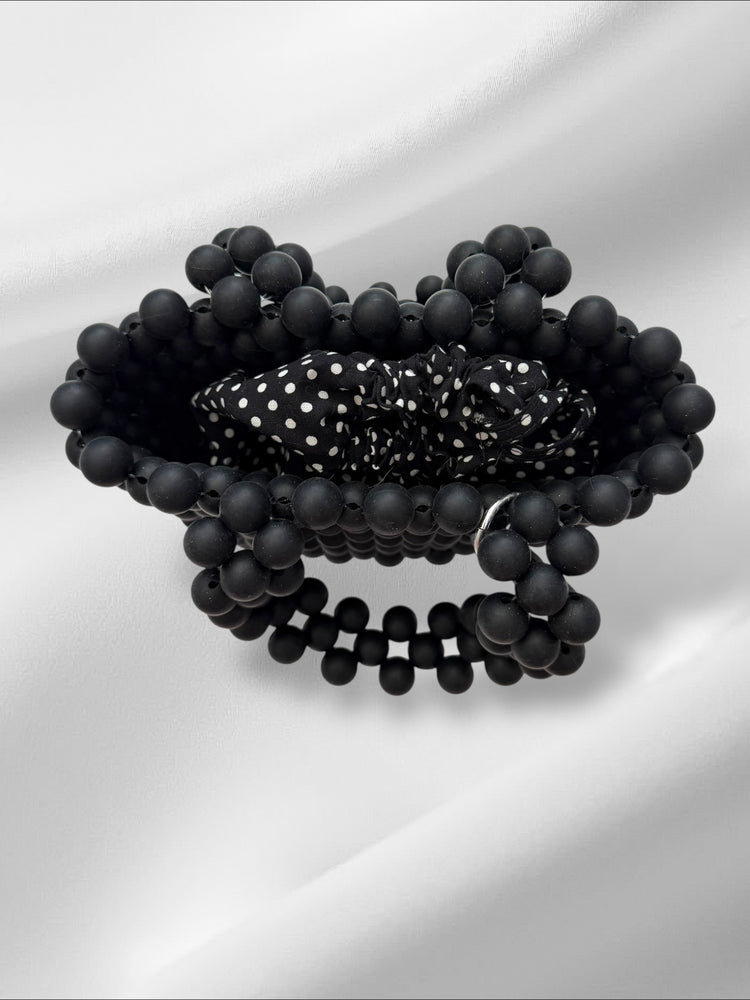 Black beaded handmade bag with a polka dot pattern drawstring pouch on a white background