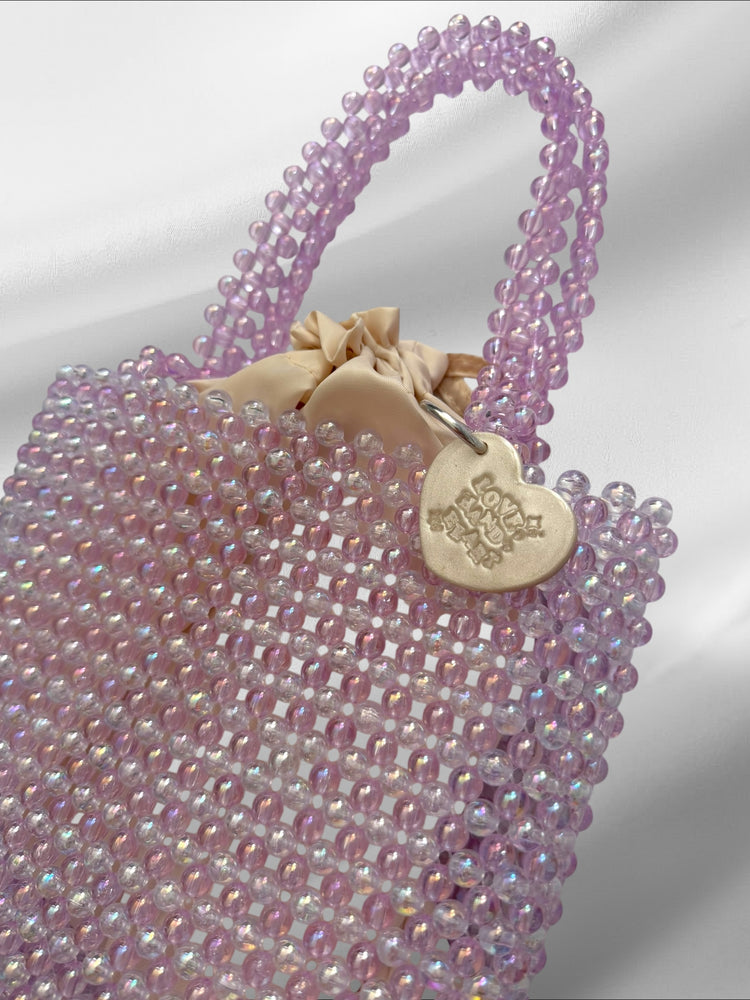 Purple beaded handbag with a heart-shaped tag on a white background