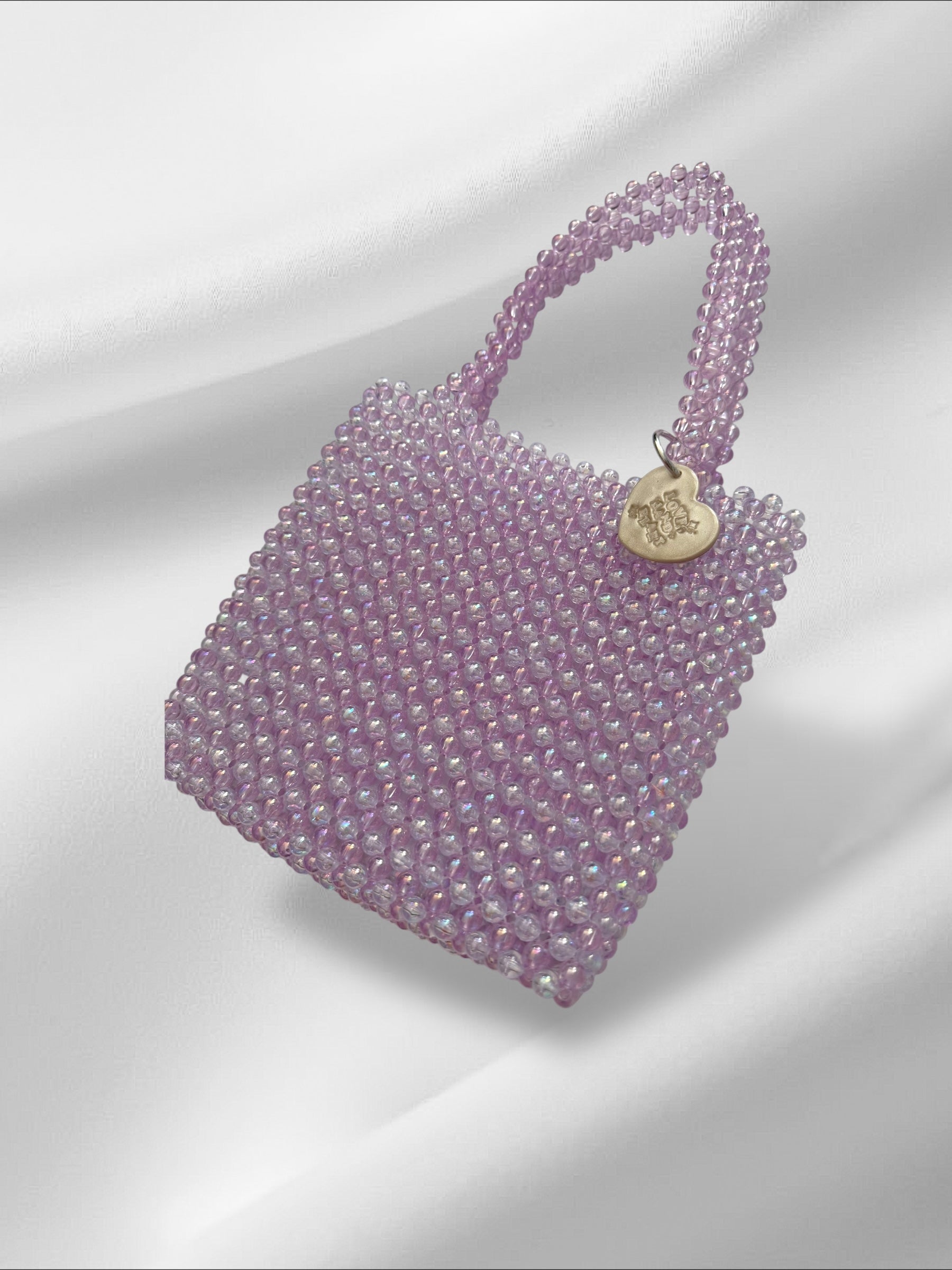 Purple beaded handbag with a heart charm on a light gray background