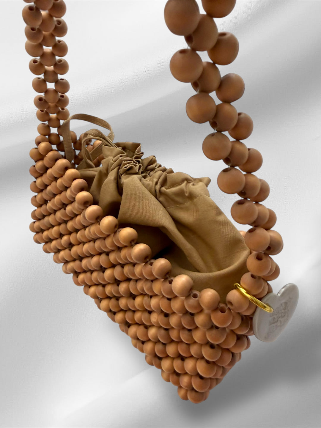 Handmade purse with wooden beads and a small heart tag on a light gray background