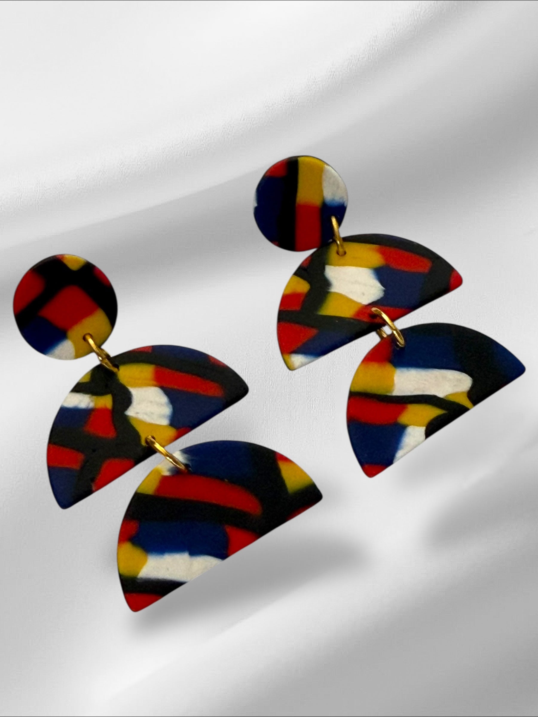 Colorful abstract earrings on a reflective surface