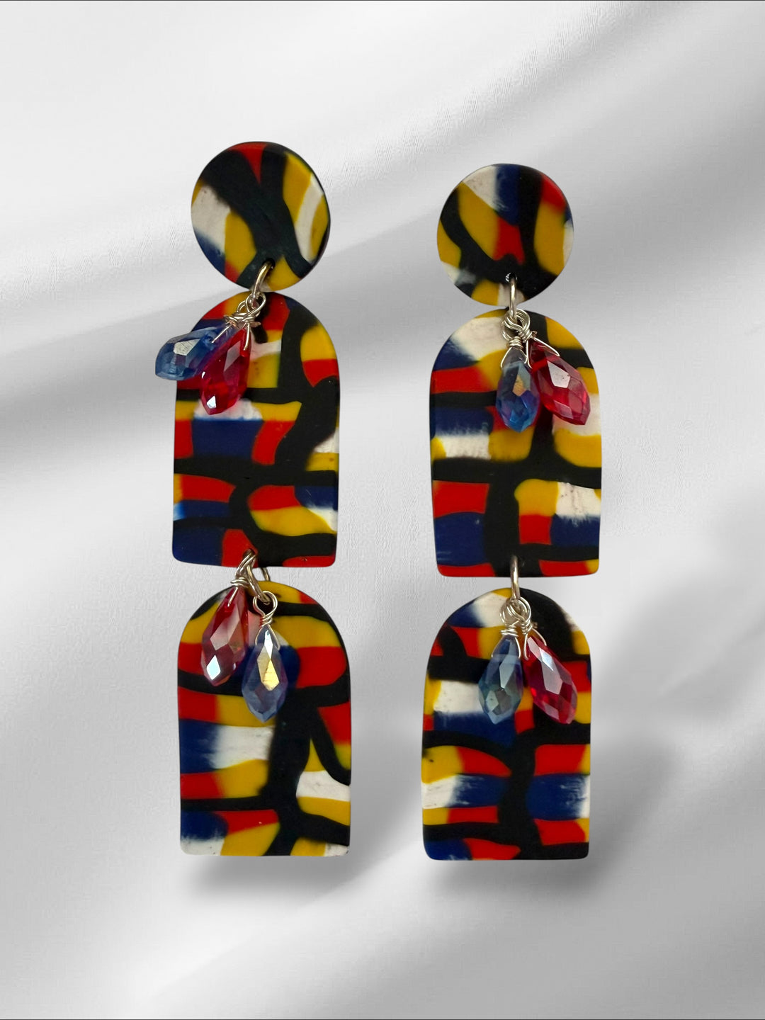 Colorful abstract-patterned earrings on a light gray background