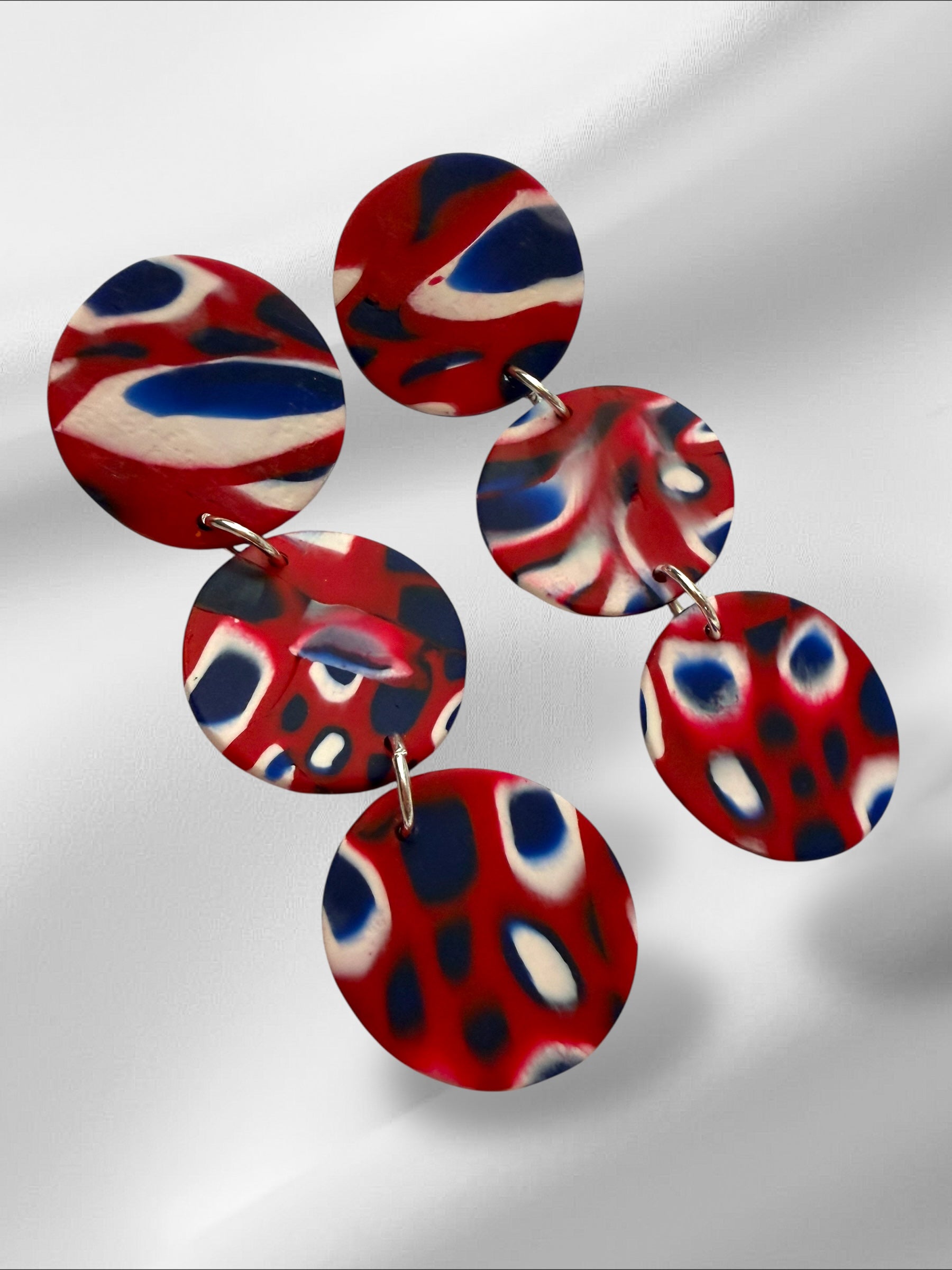 Set of red, blue, and white marbled earrings on a light gray background