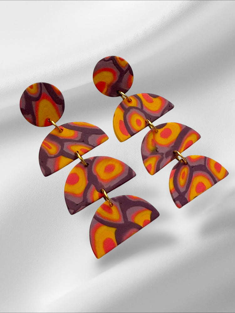 Colorful abstract earrings on a reflective surface