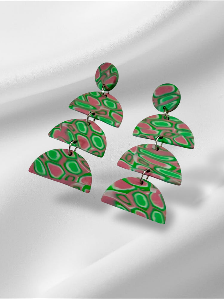 Colorful layered earrings on a reflective surface