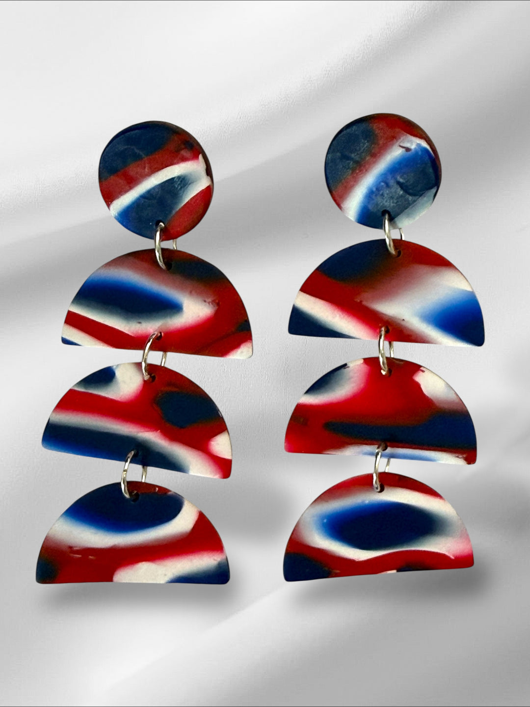 Colorful layered earrings on a reflective surface