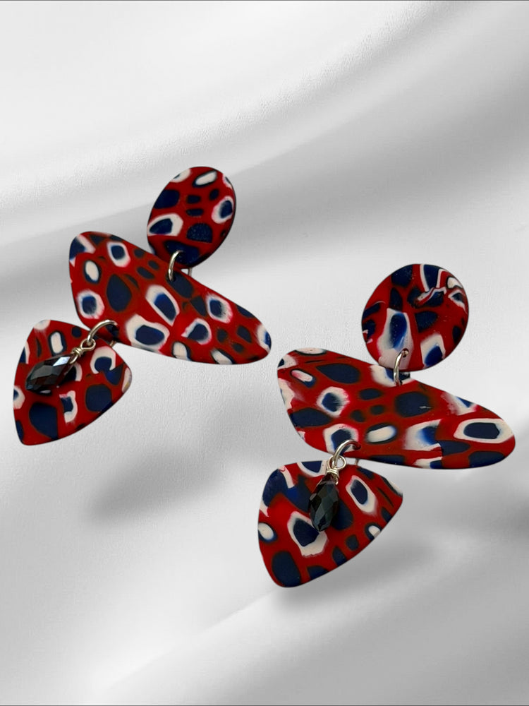 Red, blue, and white patterned earrings on a white background