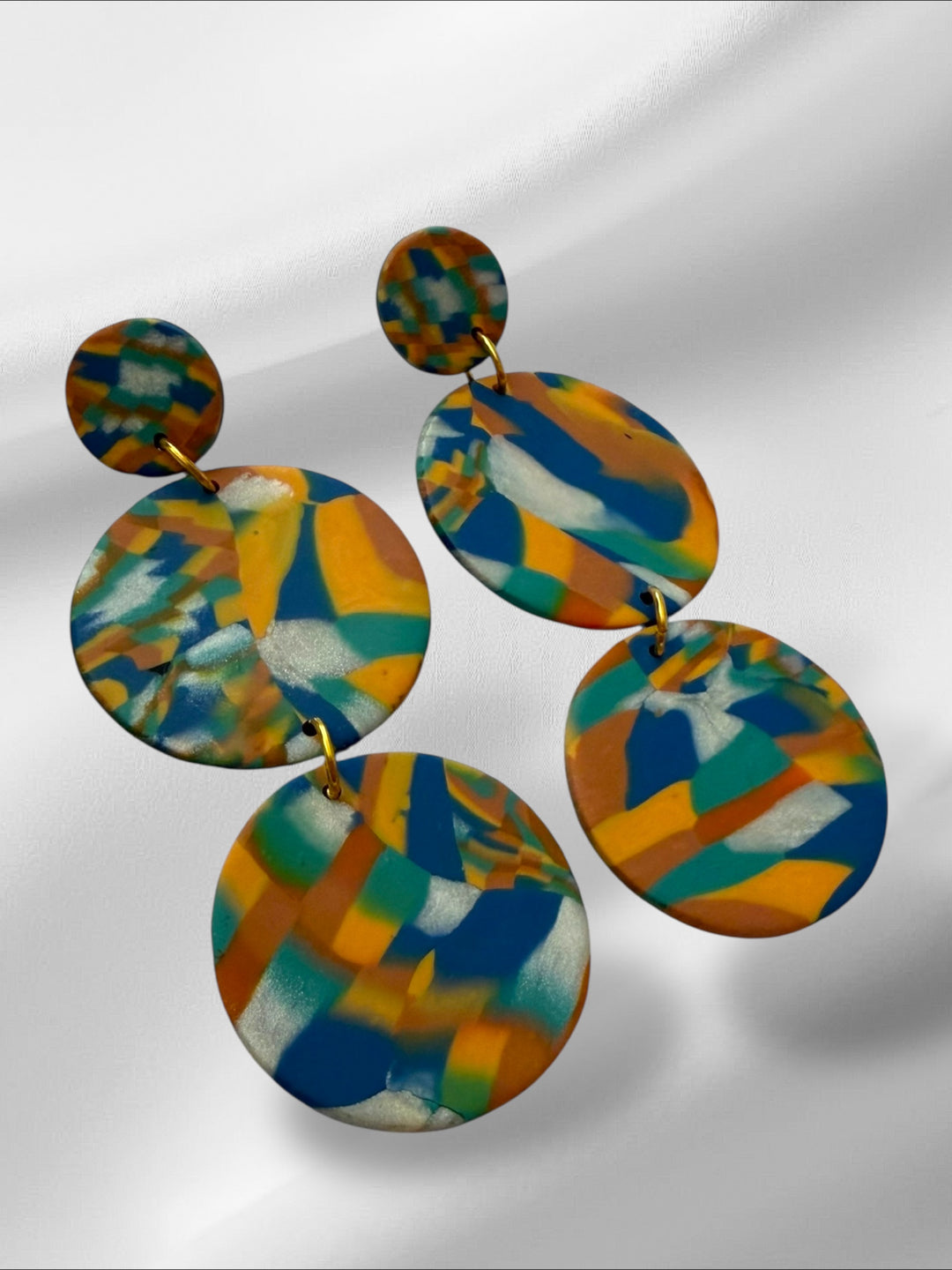 Colorful abstract-patterned earrings on a light gray background
