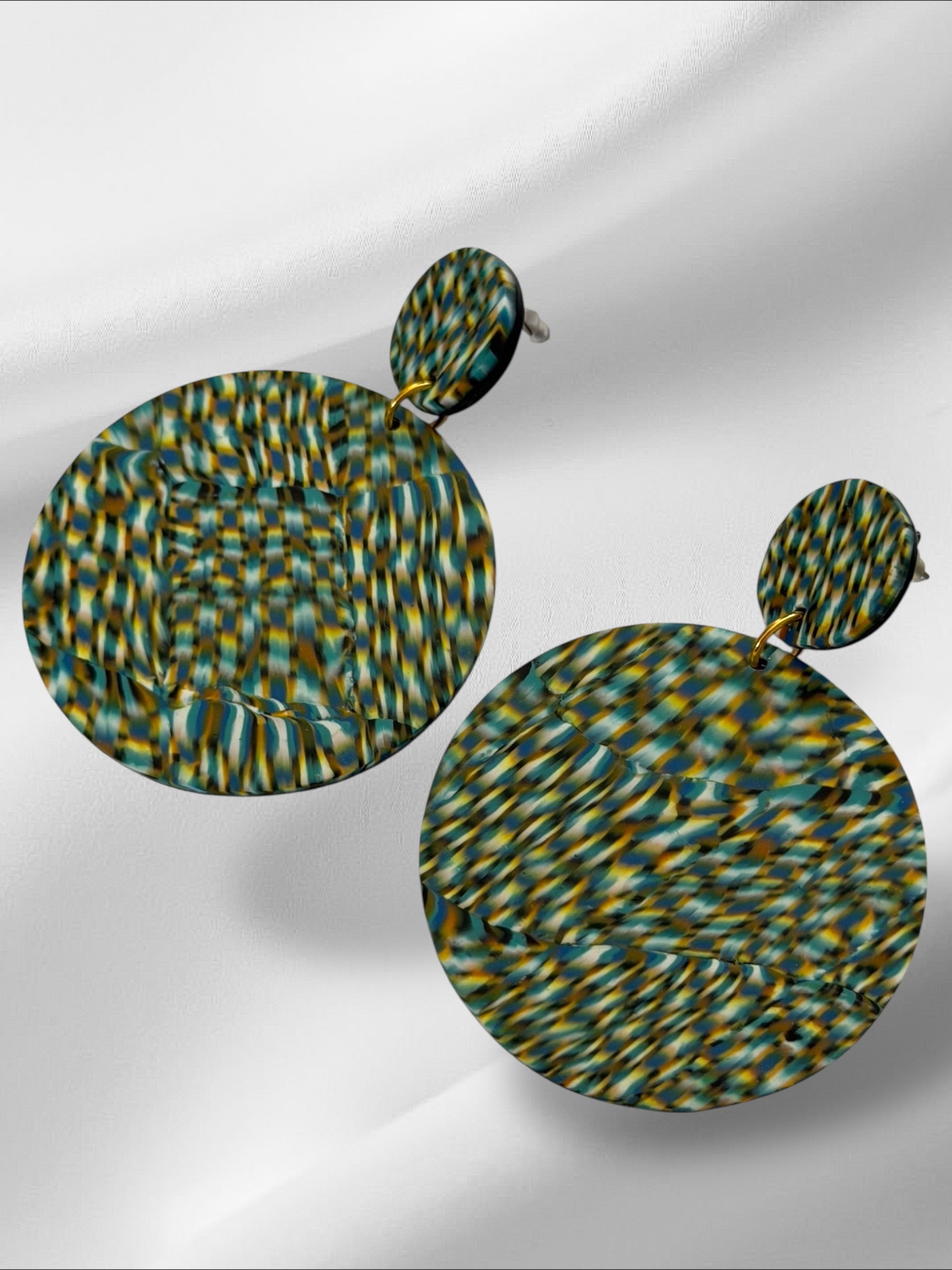 Pair of round earrings with a pattern on a light gray background
